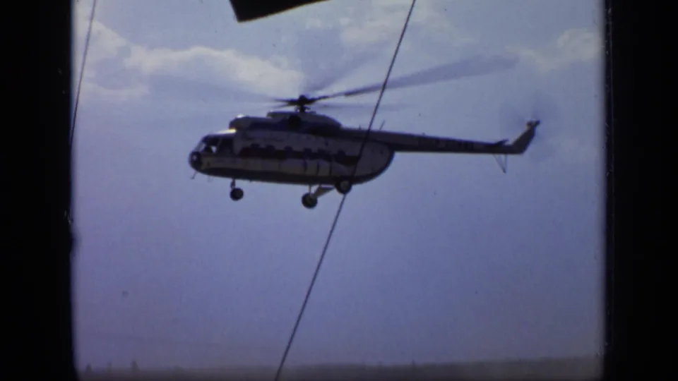 1971 Moscow 8mm frame of a helicopter in flight against a hazy sky, with visible film edge and foreground diagonal line.