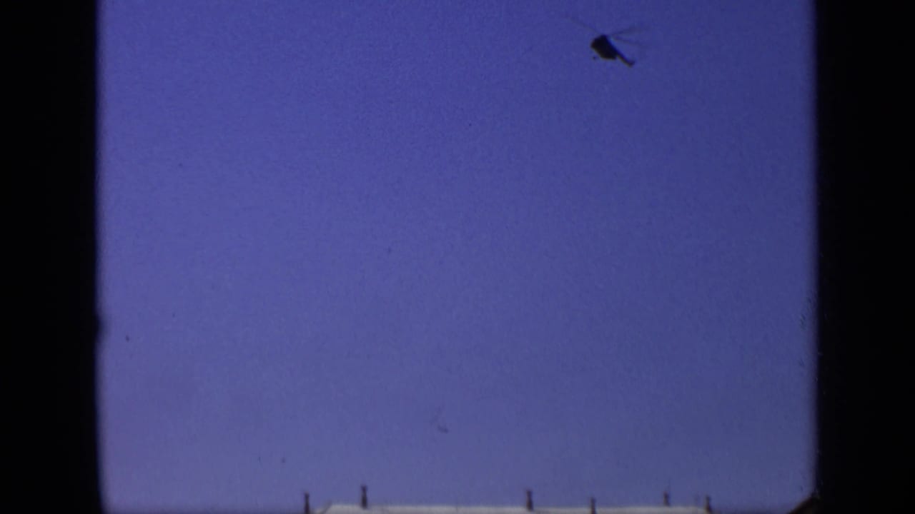 1971 Moscow 8mm frame showing open blue sky, dark gate or window edges, and a small aircraft shape near the top right.