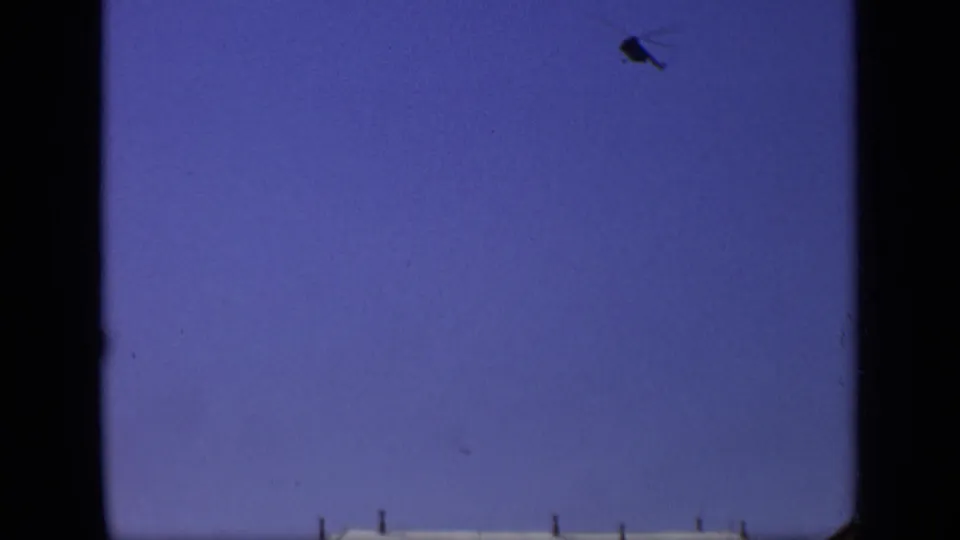 1971 Moscow 8mm frame showing open blue sky, dark gate or window edges, and a small aircraft shape near the top right.