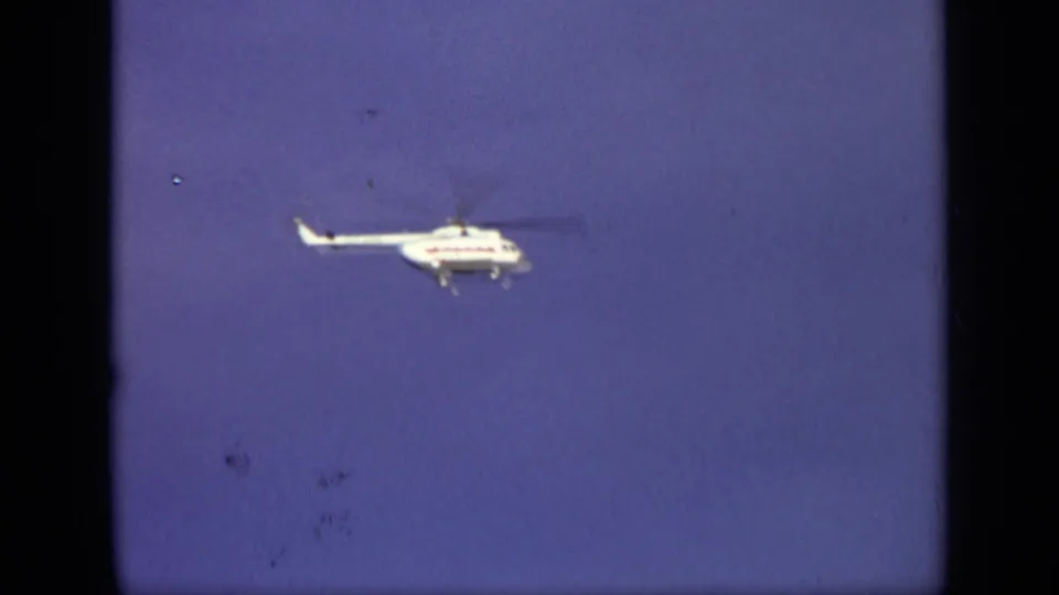 1971 Moscow 8mm frame showing a white helicopter moving through blue sky, with dark frame borders and visible film specks.