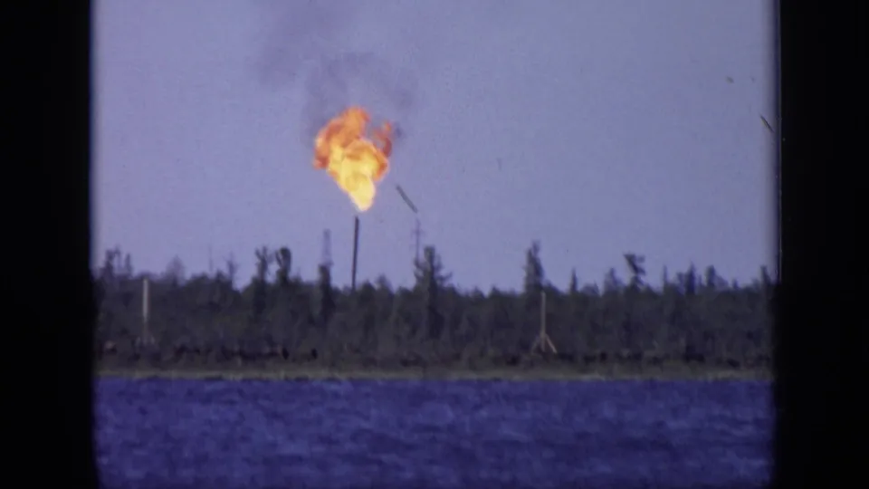 An orange flare burns above a forested shoreline across the lake in 1971 8mm footage attributed to Moscow, Russia.