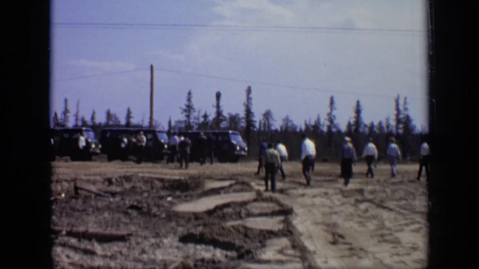 A wider 1971 Moscow construction-site view shows workers crossing a dirt lot near vehicles, with trees along the horizon.
