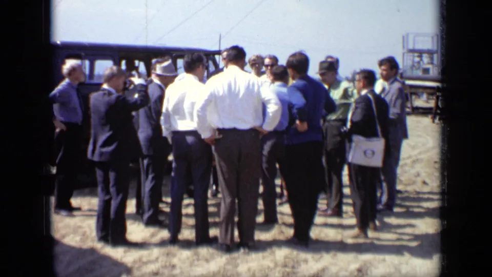 1971 Moscow 8mm frame showing a group of men assembled near a van, apparently in discussion at an outdoor site.