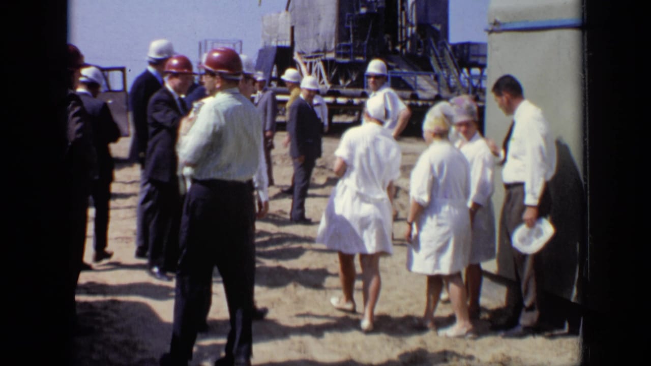 Adults at a Moscow industrial site in 1971 stand and converse beside heavy metal equipment or construction structure.