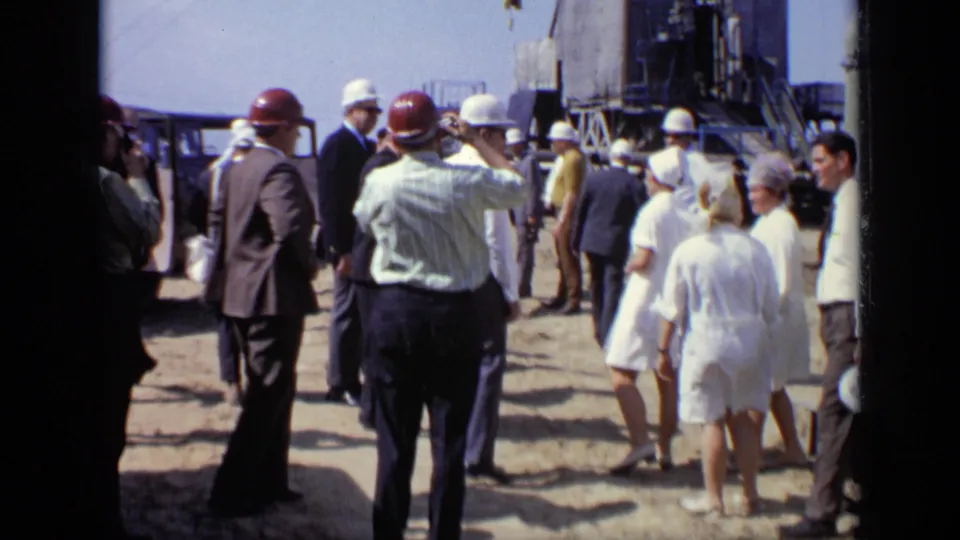 Home-movie view of adults in hard hats and formal clothing gathered at a 1971 Moscow industrial location.