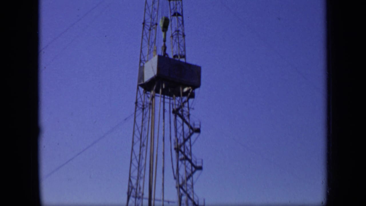 Low-angle view of a metal drilling tower against a blue sky.