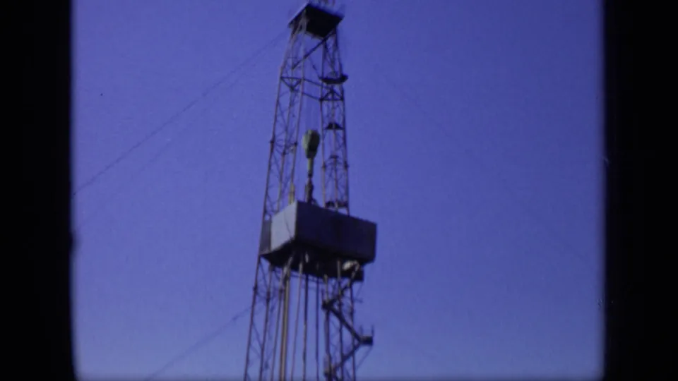 A 1971 Moscow industrial frame shows the upper structure of an oil rig, including its platform, cables, and tower bracing.