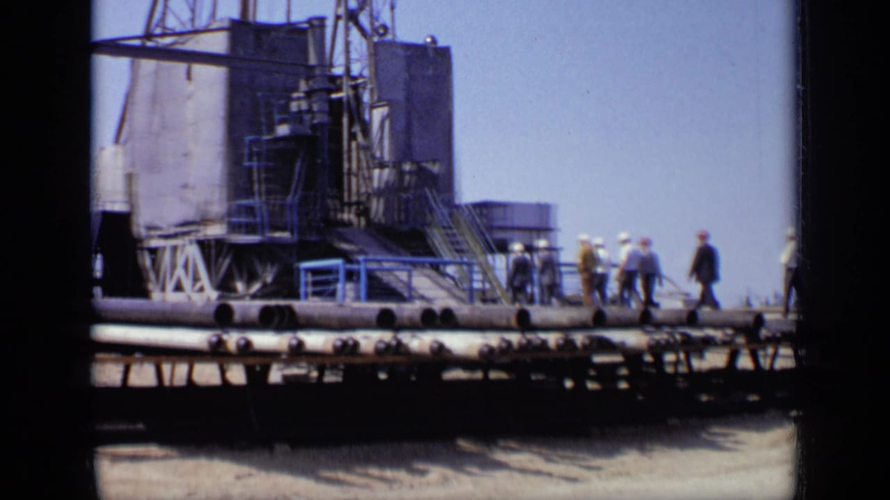 1971 Moscow 8mm frame showing industrial equipment, pipe runs, and several people walking near a large facility structure.