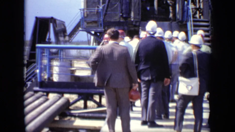 Handheld 8mm view of men in hard hats and suits gathered on a platform at a Moscow industrial site in 1971.
