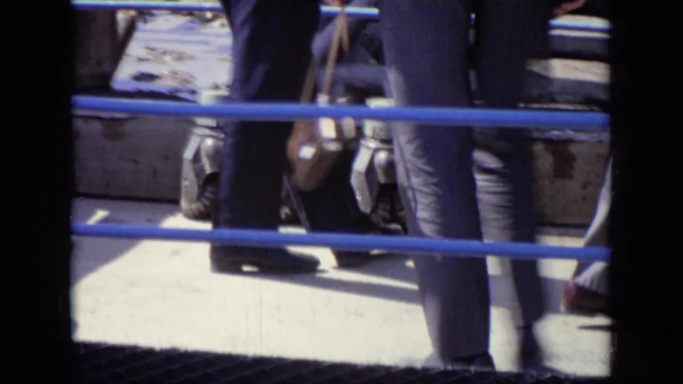 In 1971 Moscow footage, men pass behind blue platform railings near metal equipment at an outdoor industrial site.