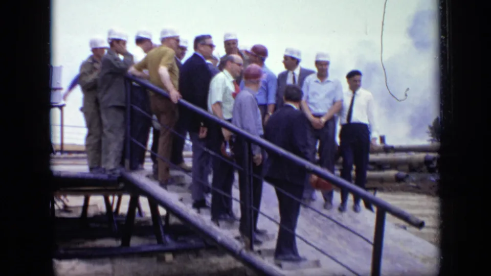 Closer 1971 Moscow view of hard-hatted workers and suited visitors gathered on a ramp at an outdoor industrial site.