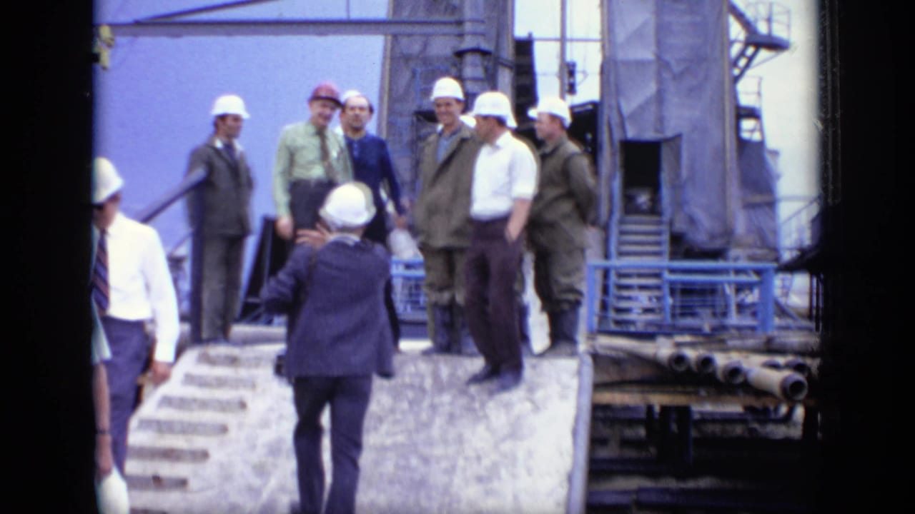 A 1971 Moscow industrial-site view shows hard-hatted men and officials standing on a raised ramp near scaffolding, pipes, and concrete steps.