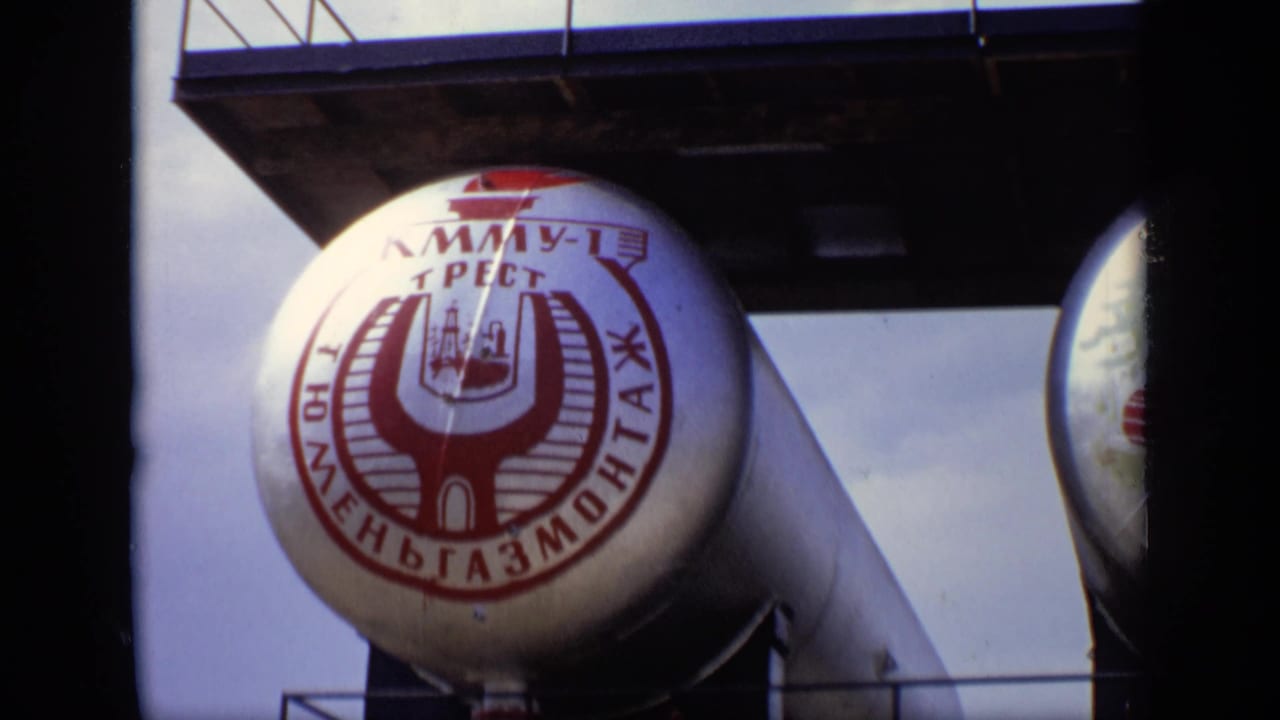 Large cylindrical tank with red Cyrillic lettering and an industrial logo under a platform.