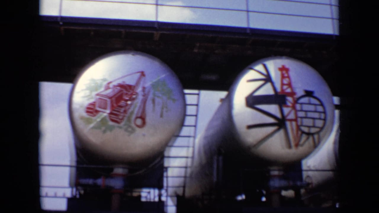 1971 Moscow 8mm frame showing painted cylindrical tanks with industrial imagery and Soviet-style symbols under an overhead structure.