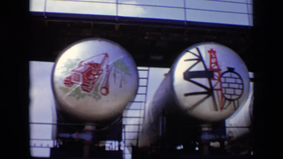 1971 Moscow 8mm frame showing painted cylindrical tanks with industrial imagery and Soviet-style symbols under an overhead structure.