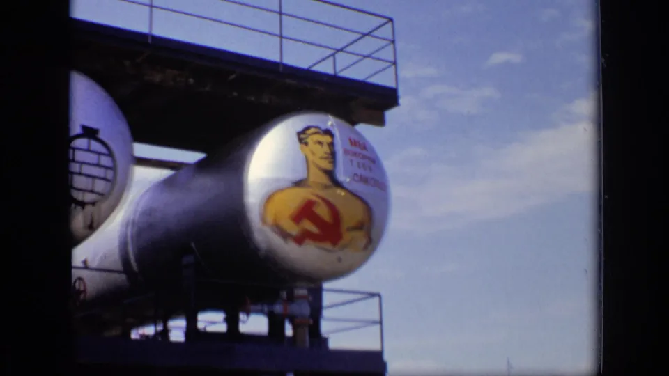 1971 Moscow 8mm view of a painted worker with hammer and sickle on a tank, with platform railings and open sky visible.
