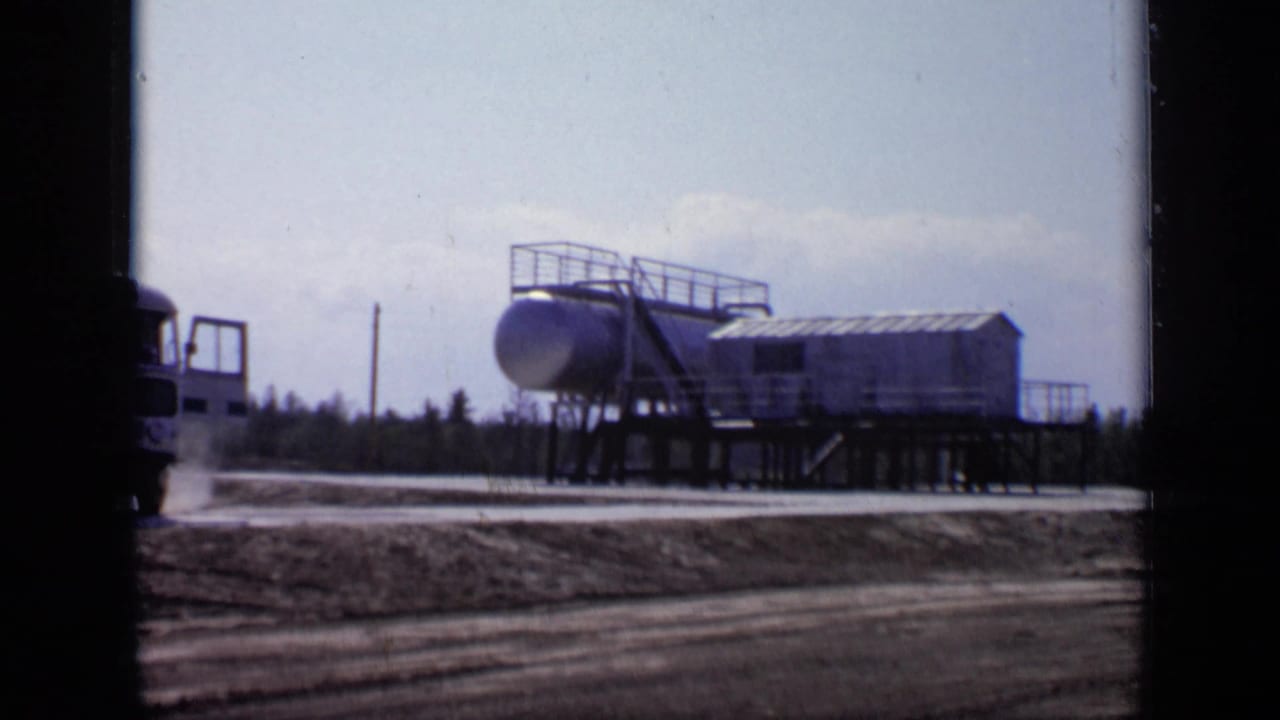 1971 Moscow 8mm frame showing an elevated industrial tank and platform structure near a roadside area.