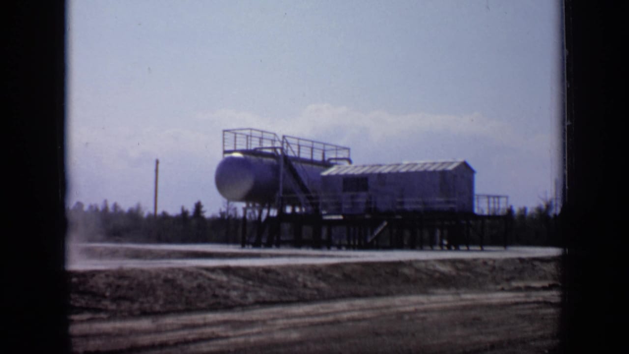 1971 Moscow 8mm view of a raised tank installation with a small building and railings against a pale sky.