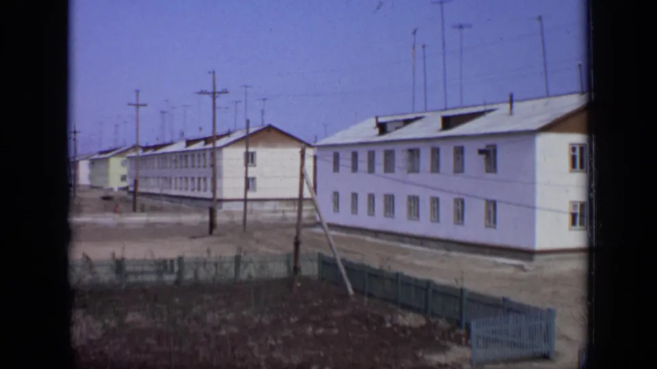 1971 Moscow 8mm view of white low-rise residential blocks, roof antennas, utility poles, and fenced open ground.