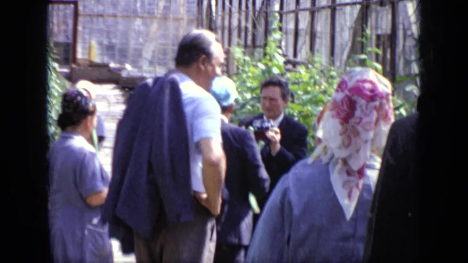 Adults in suits and headscarves gather near tall plants in a Moscow greenhouse, based on the supplied clip metadata.