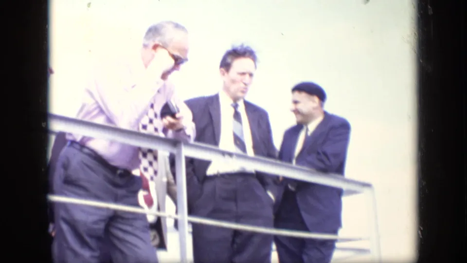 Men in suits stand near a railing in bright light during the same 1971 Moscow home-movie sequence.