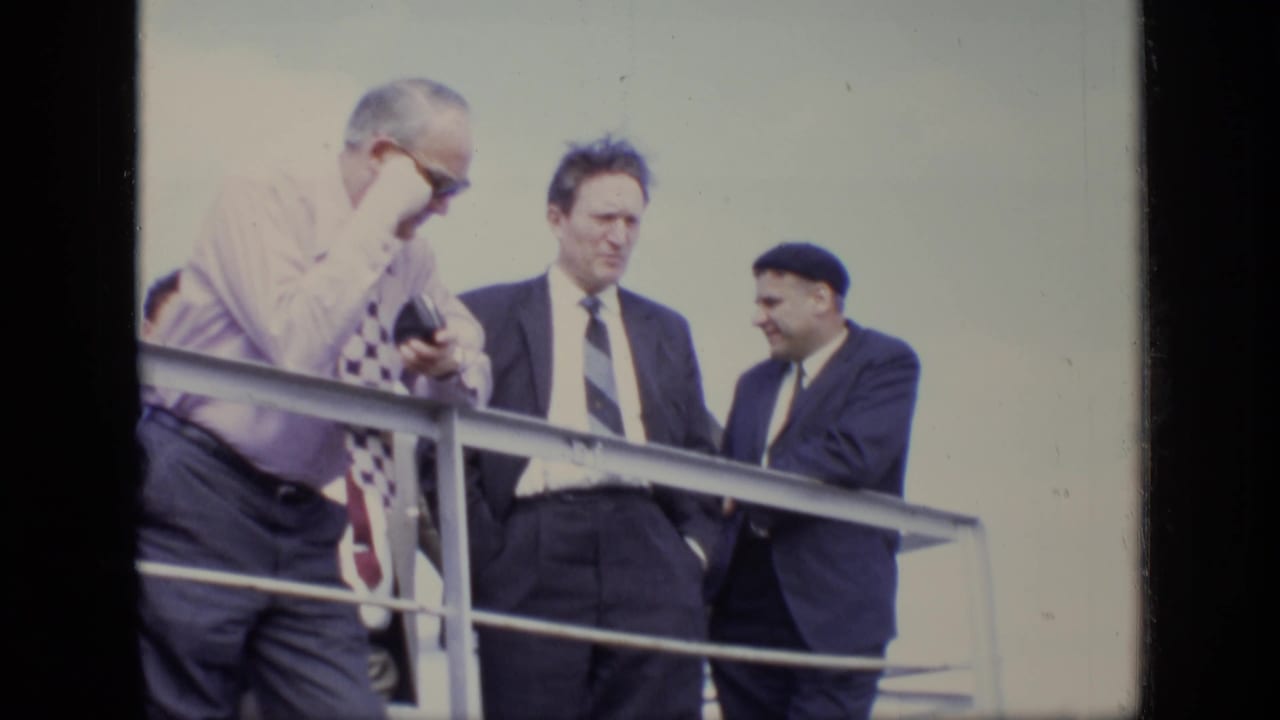 Three men in formal clothing stand near a metal railing in the 1971 Moscow clip, with soft focus and faded color.