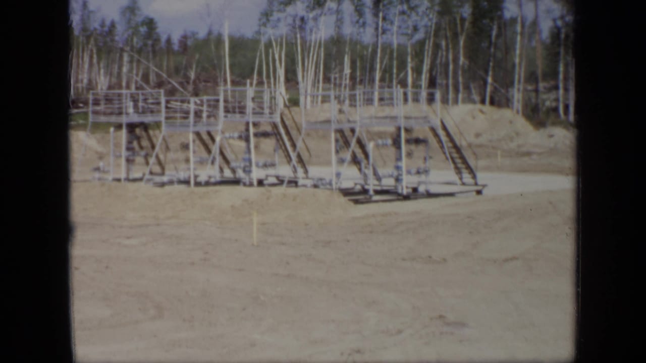 Metal platform and railings on sandy ground with trees behind the structure.