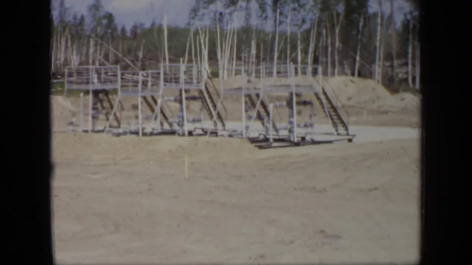 Closer 1971 Moscow view of an industrial metal platform with railings, supports, steps, and birch trees beyond.