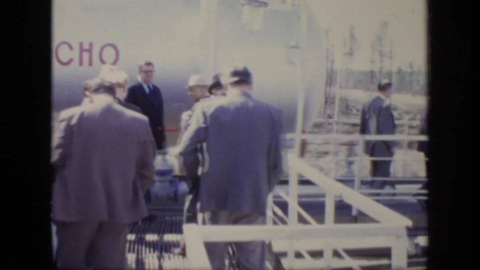 1971 Moscow inspection scene with suited men on a metal walkway near railings and a large structure bearing partial lettering.