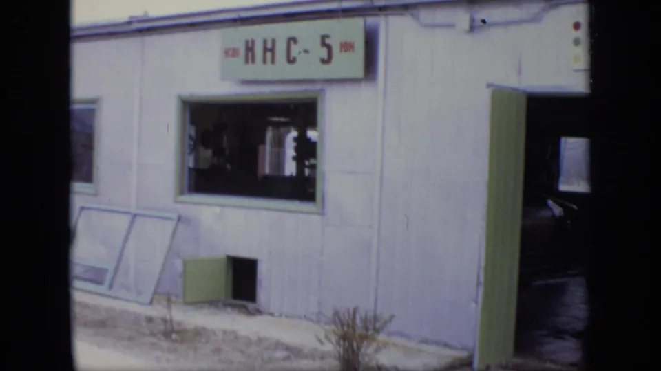 1971 Moscow frame showing the same white building, visible signage, green trim, open doorway, window, and a dark vehicle or interior edge.
