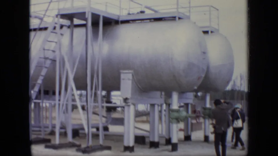 Large silver storage tanks at a Moscow industrial site appear beside ladders and pipework, with men visible below.
