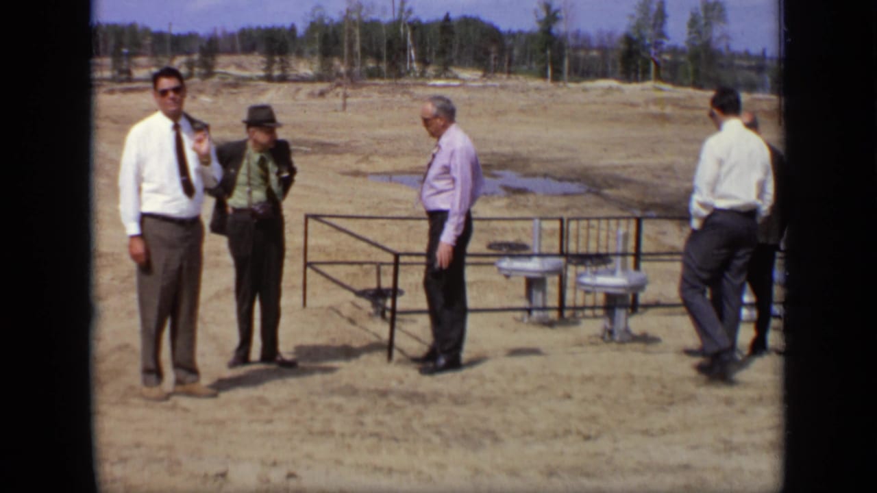 A small group of adult men in formal clothing stands near metal railings and exposed pipes at the Moscow site.