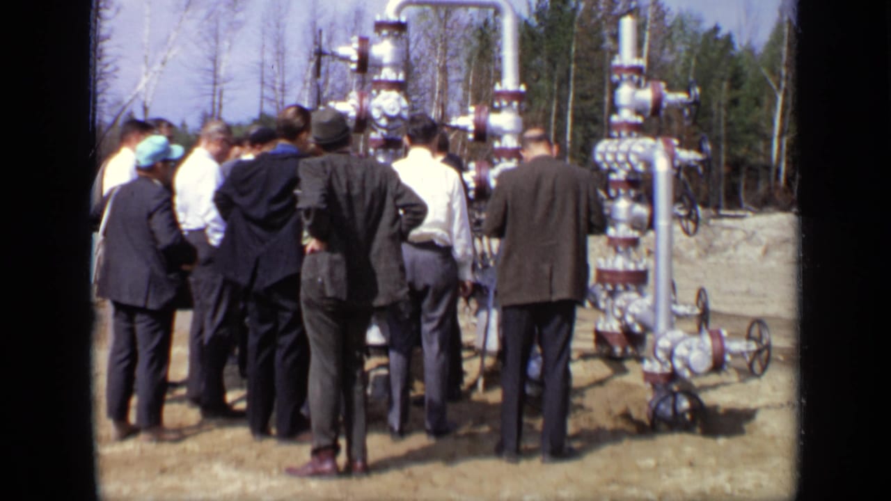 Men in suits and hats cluster beside tall valves and pipe assemblies during an apparent 1971 Moscow technical inspection.