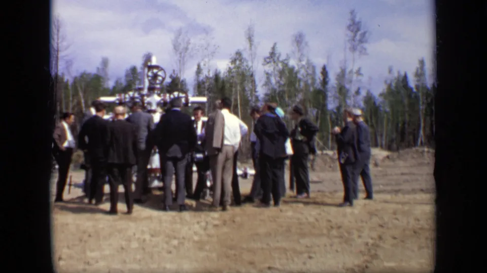 The final frame shows men still assembled around valve equipment outdoors near Moscow, with sparse trees in the background.