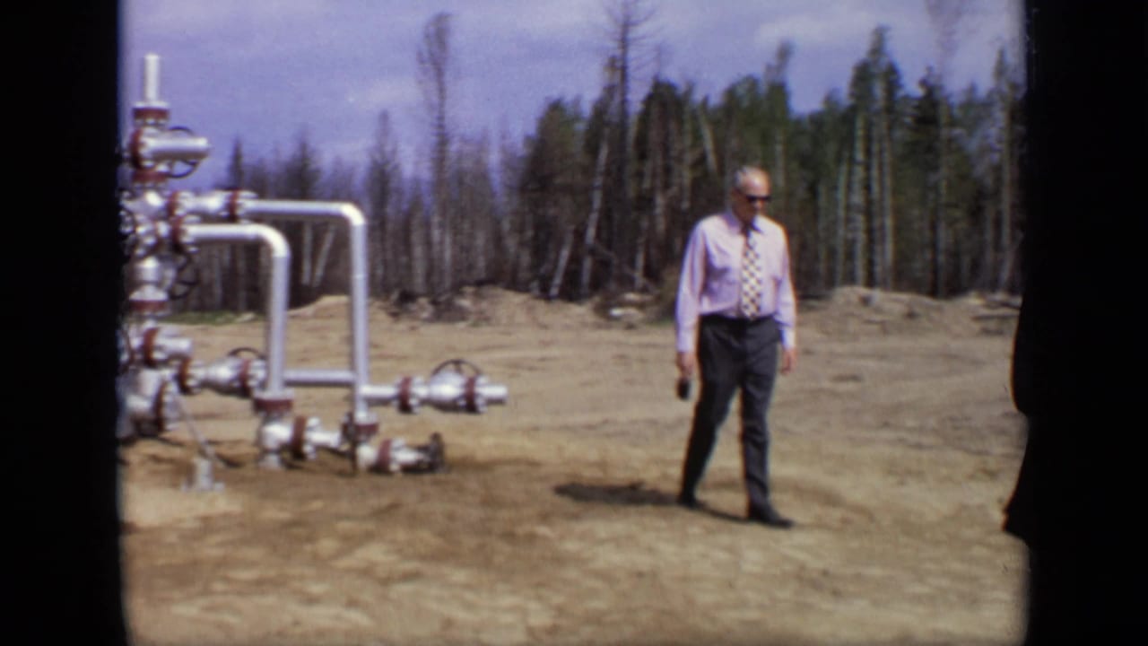 1971 Moscow footage showing a man in a shirt and tie standing near industrial pipework in a wooded clearing.