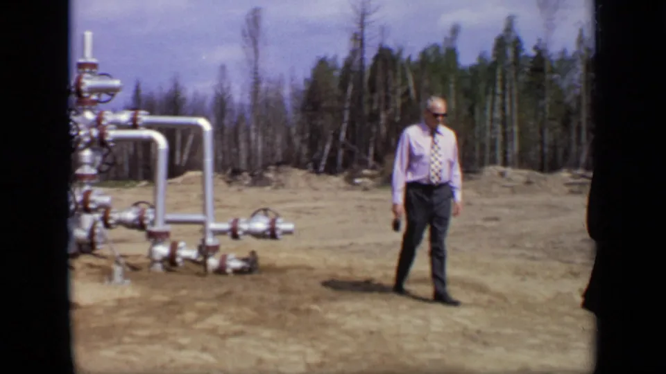 1971 Moscow footage showing a man in a shirt and tie standing near industrial pipework in a wooded clearing.