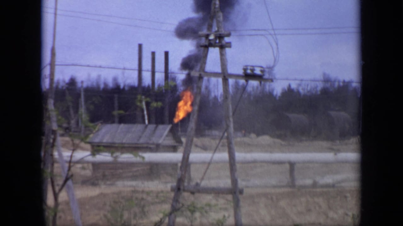 1971 Moscow 8mm frame showing a small fire producing dark smoke near wooden utility poles, power lines, and low worksite structures.