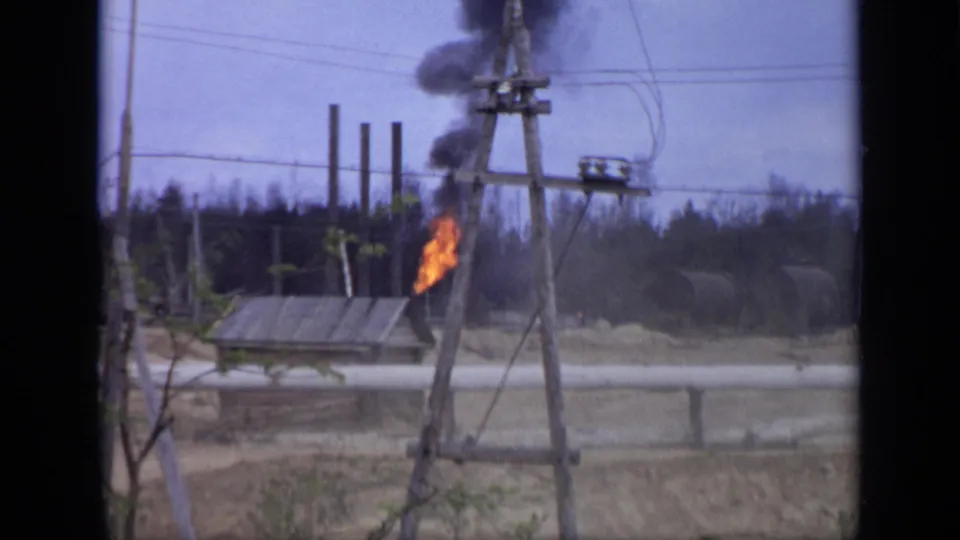 1971 Moscow 8mm frame showing a small fire producing dark smoke near wooden utility poles, power lines, and low worksite structures.