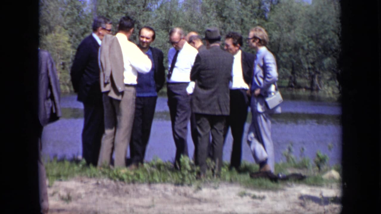 A small group of men continues talking near the water's edge.