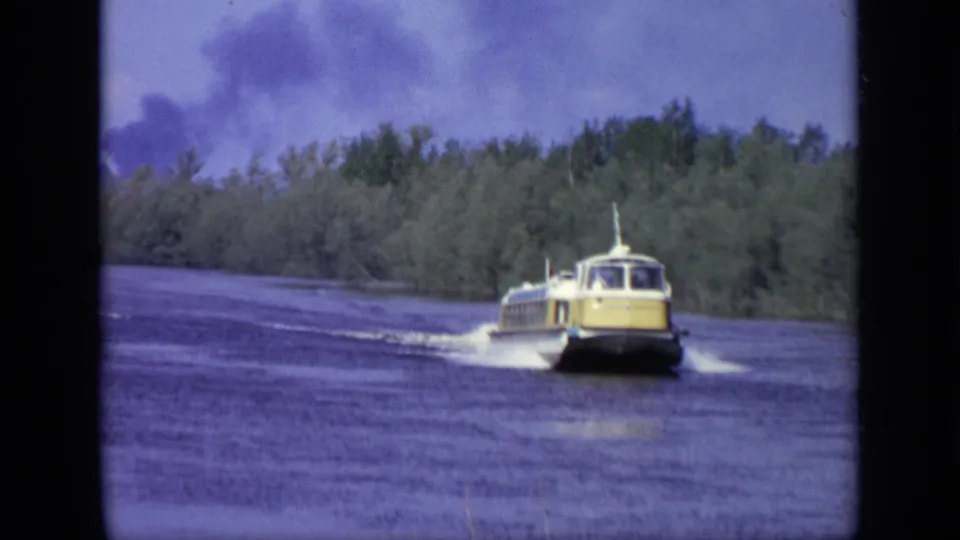 A 1971 Moscow 8mm frame shows the yellow hydrofoil crossing the lake under blue-purple sky and dense shoreline trees.