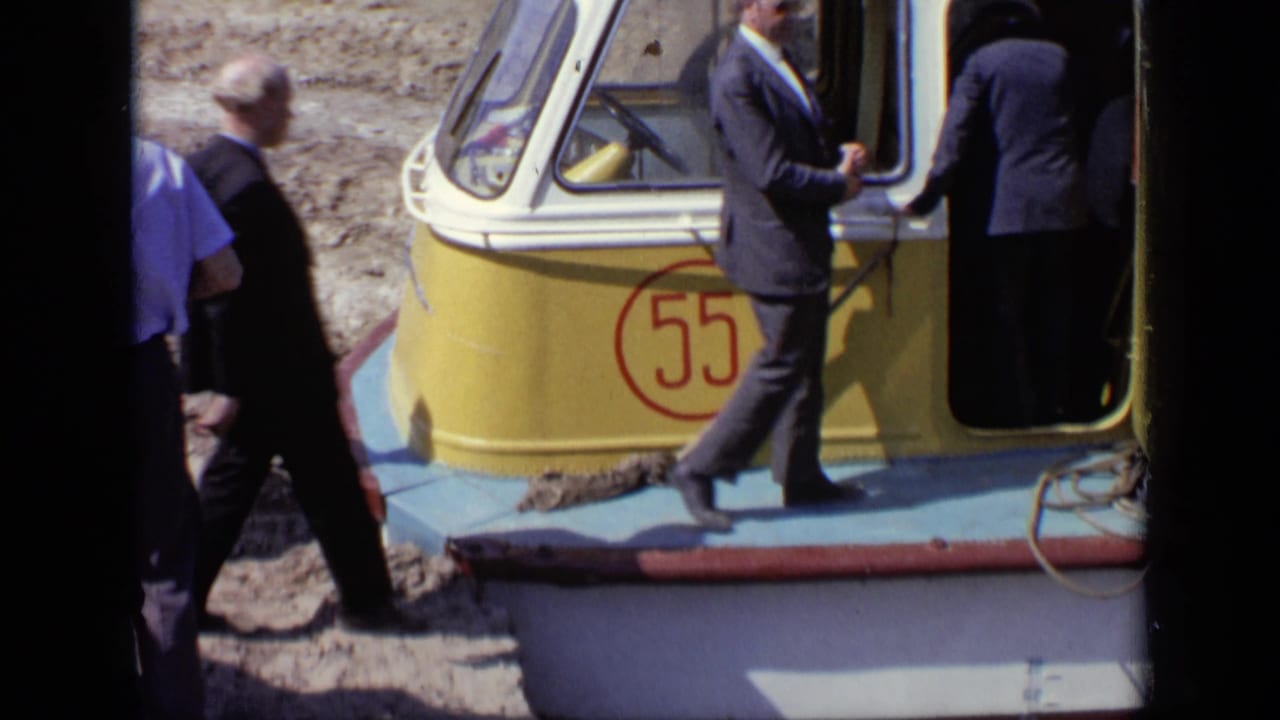 Suited men gather at the open door of a yellow and blue boat marked 55 in 1971 Moscow home-movie footage.