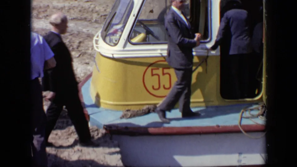 Suited men gather at the open door of a yellow and blue boat marked 55 in 1971 Moscow home-movie footage.
