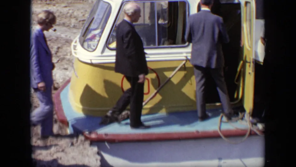 A group of men in suits walk along the narrow deck toward the open door of the yellow boat in Moscow, 1971.