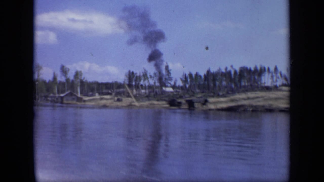 1971 Moscow river view with low shore buildings, trees, and a dark smoke plume rising in the distance.