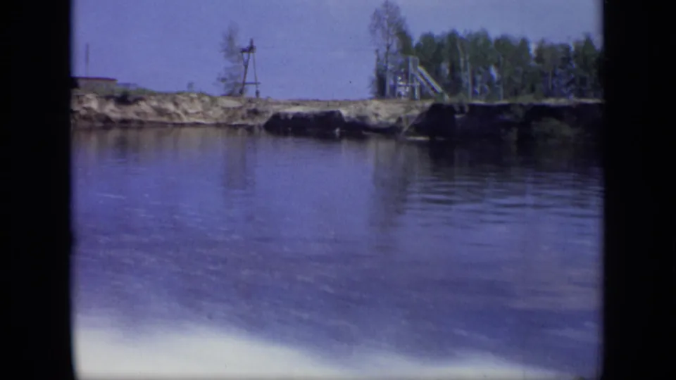 1971 Moscow-area riverside industrial scene with a small tower-like structure, shoreline equipment, trees, and water.