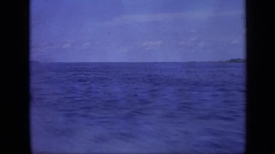 A blue-toned 8mm view shows open sea water with a low distant horizon and faint shoreline or landform at right.