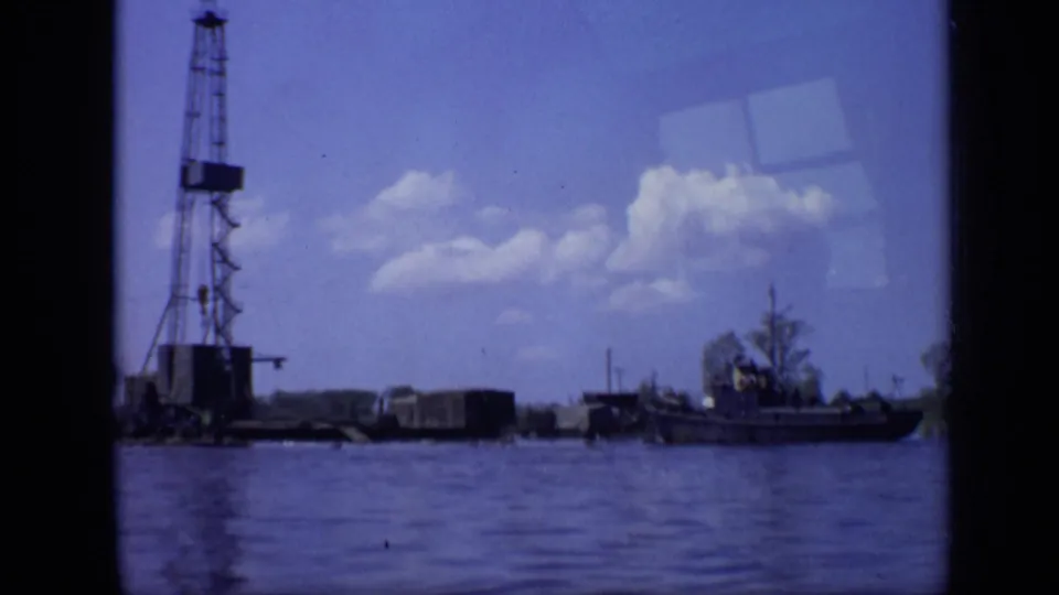 Moscow 1971 home-movie frame with the derrick partly left of center, a boat to the right, and open water filling the foreground.