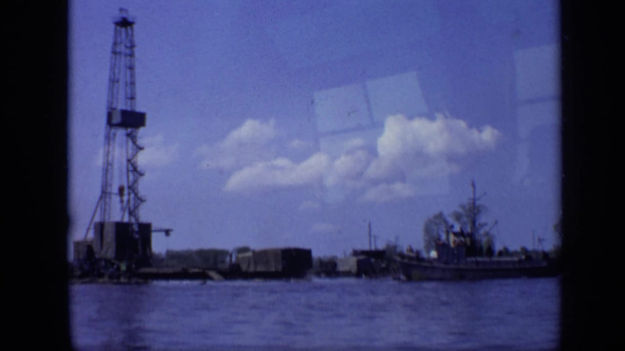 A 1971 Moscow waterfront frame shows the crane barge and nearby boat from a low, across-water home-movie viewpoint.