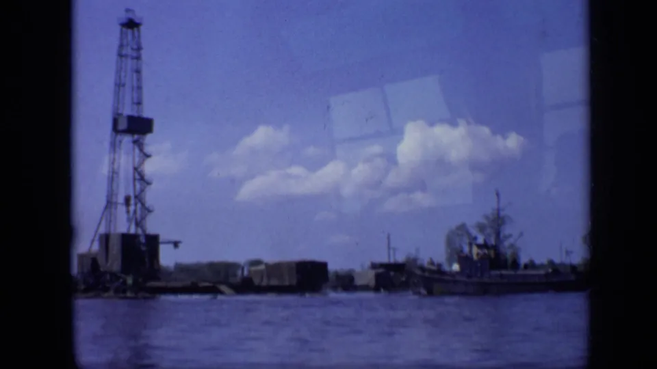 A 1971 Moscow waterfront frame shows the crane barge and nearby boat from a low, across-water home-movie viewpoint.