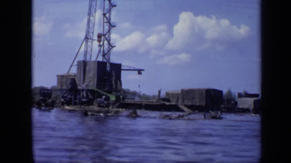 Closer 8mm view of the Moscow waterfront crane platform, with low dockside forms and rippling water in the foreground.
